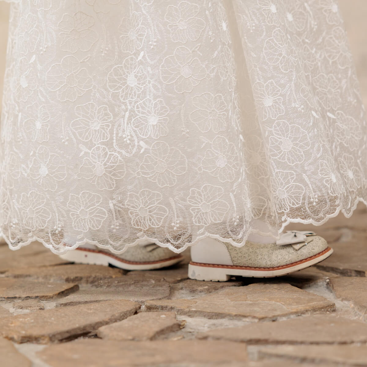 First Communion Dress with glittery shoes on a stone floor