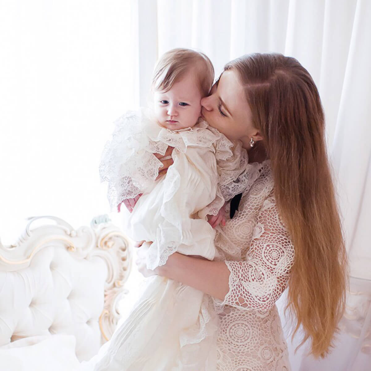 Woman holding a baby dressed in white lace outfits