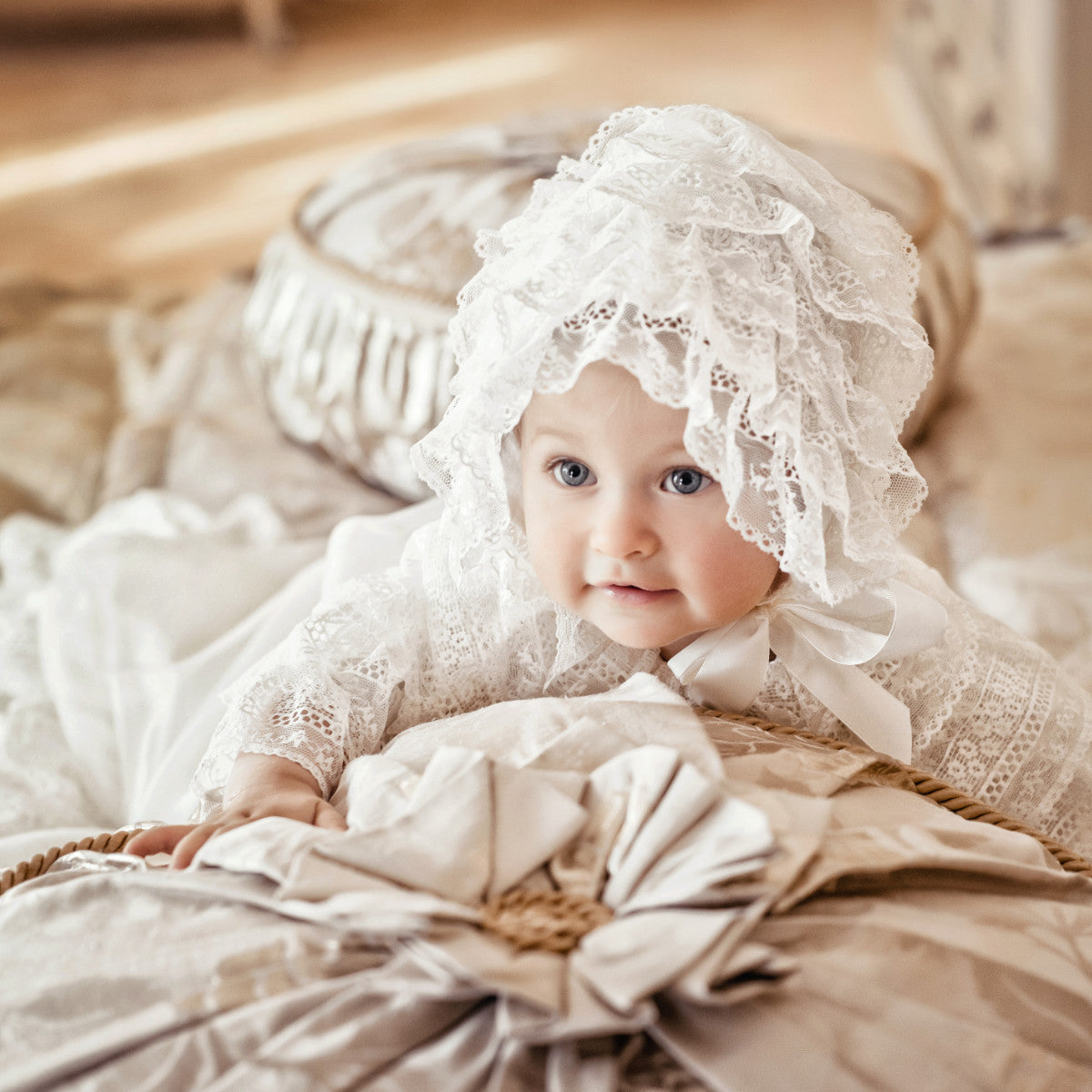 Baby wearing a lace bonnet lying on a soft surface