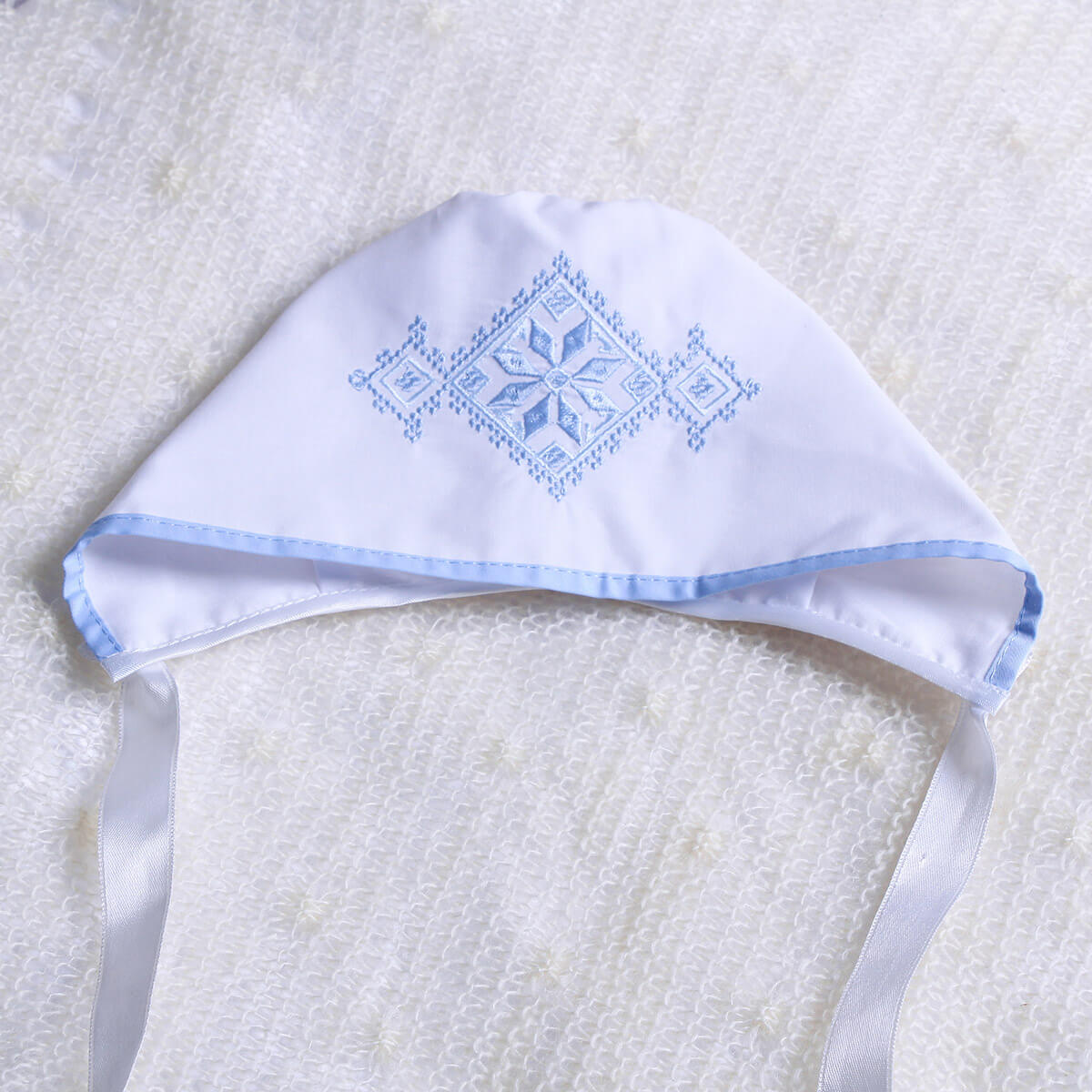 Boy Christening Hat with blue embroidery on a textured white background