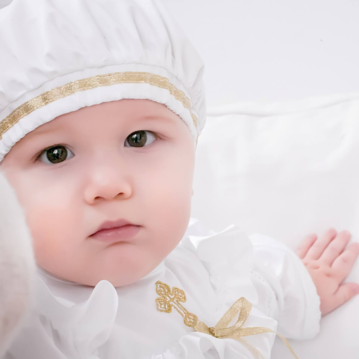 Baby in tBoy Christening Hat with gold accents on a white background