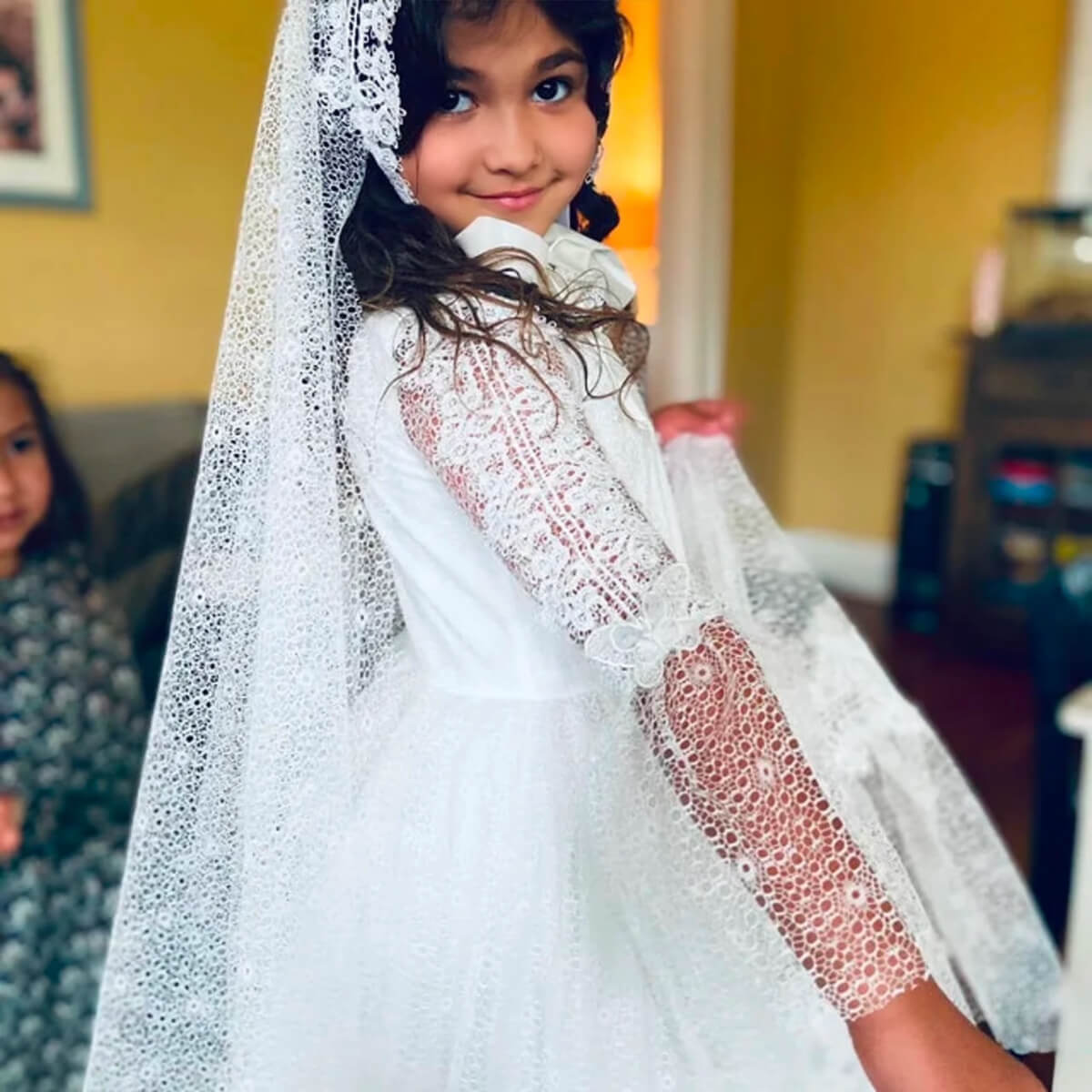 Young girl wearing Lace First Communion Dress with a blurred indoor background