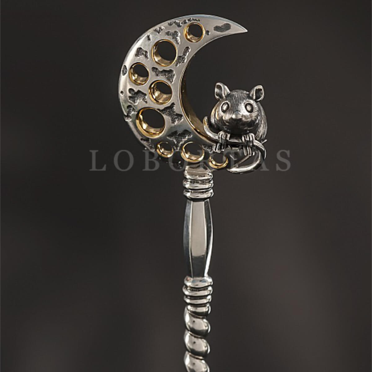 Decorative spoon with moon and mouse design on a dark background