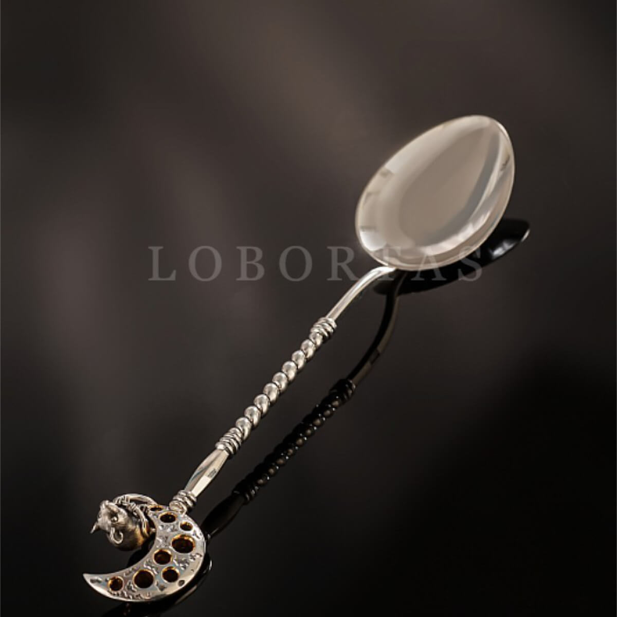 Decorative silver spoon with a moon design on a dark background, featuring the brand 'LOBORAS'.