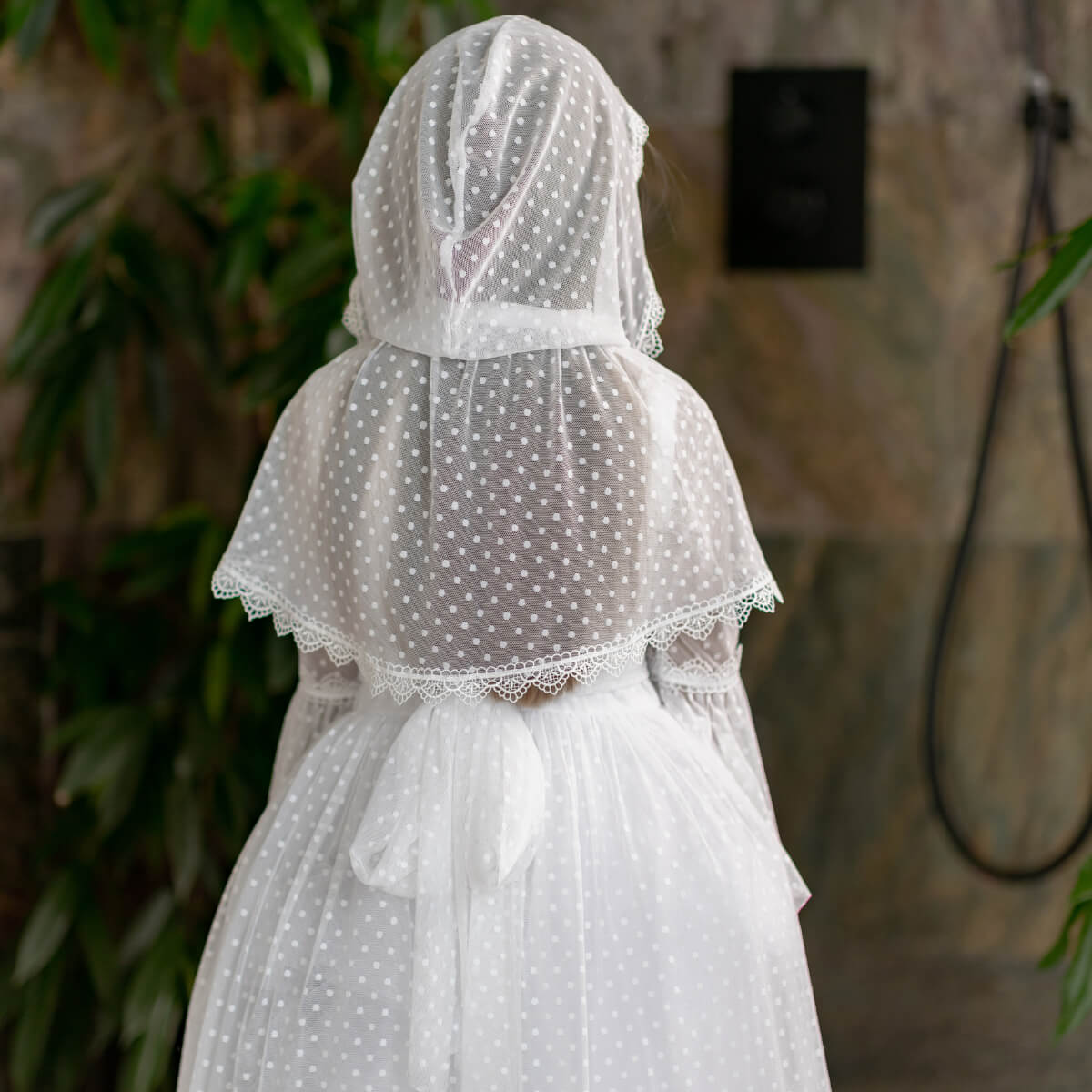Person wearing a First Communion Mantilla Veil and dress in a bathroom setting.