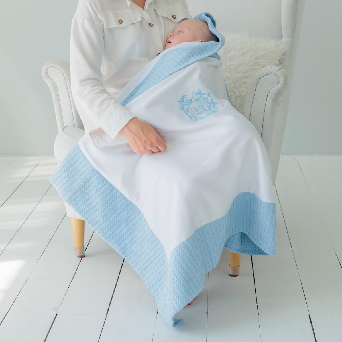 Coming Home Blanket with a logo, sitting on a white chair.