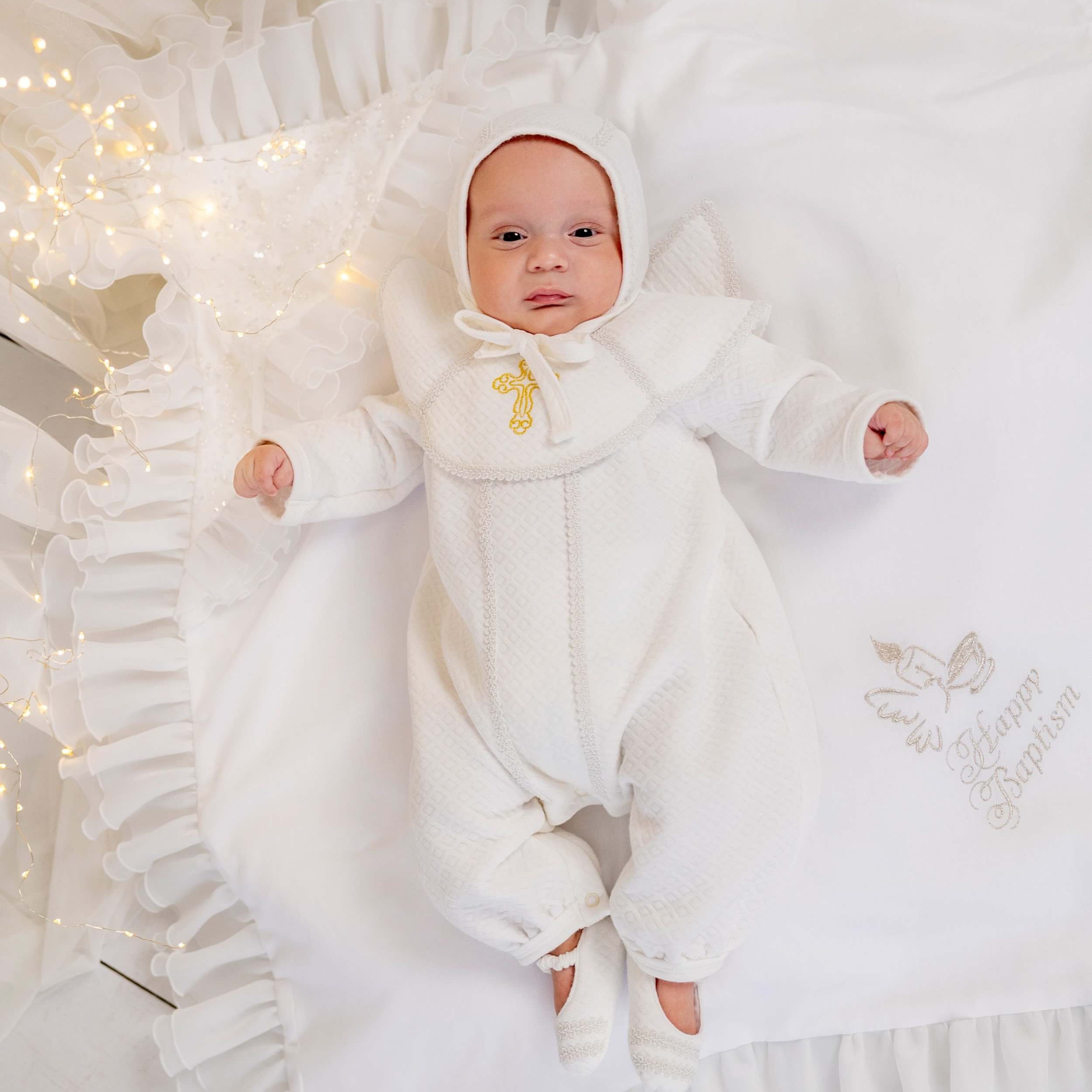 Baby in Baptism Outfit for Boys lying on a white blanket with decorative elements
