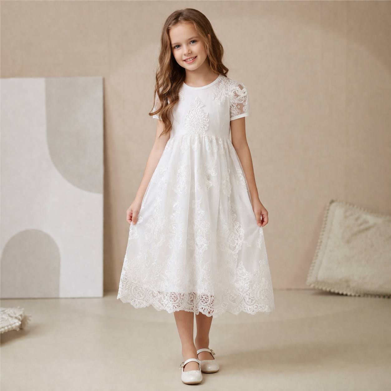 Young girl wearing ivory lace dress against a beige background
