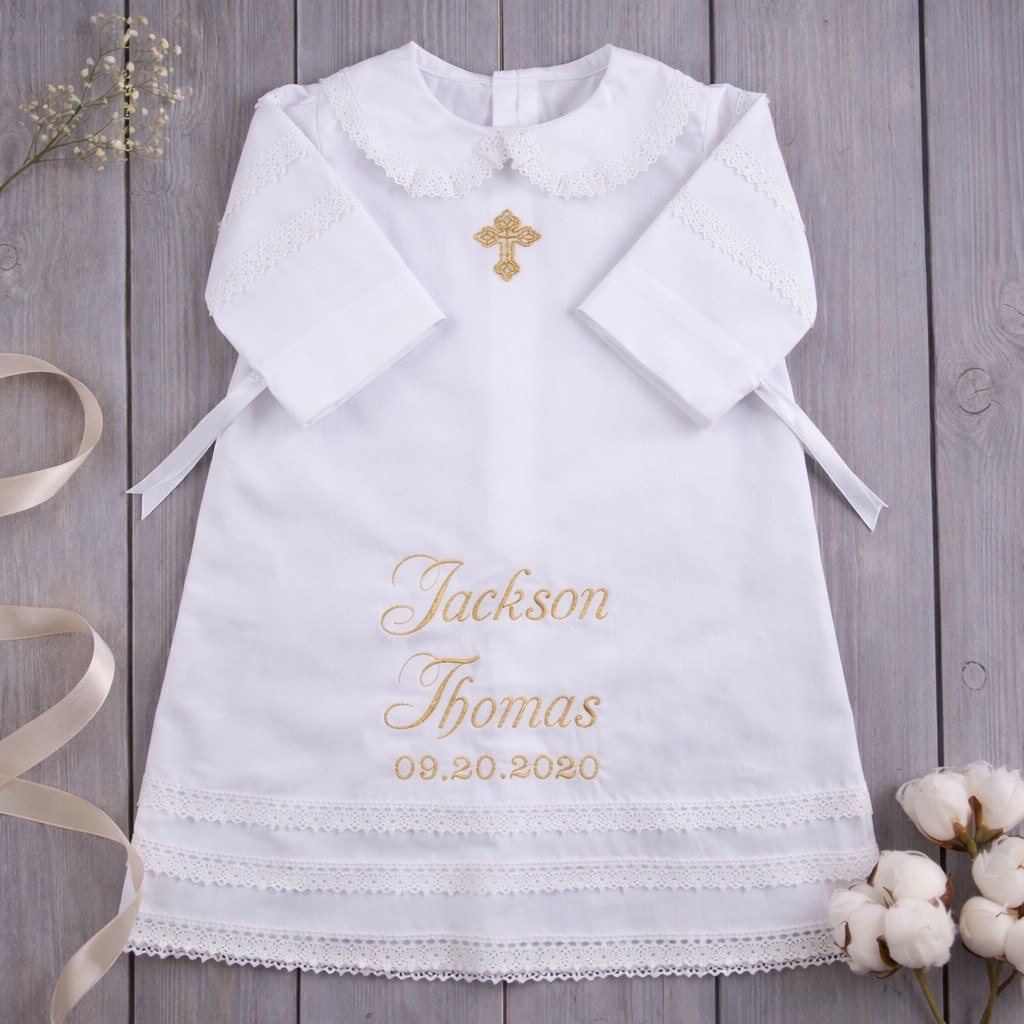 White baby outfit with embroidered name and date on a wooden background