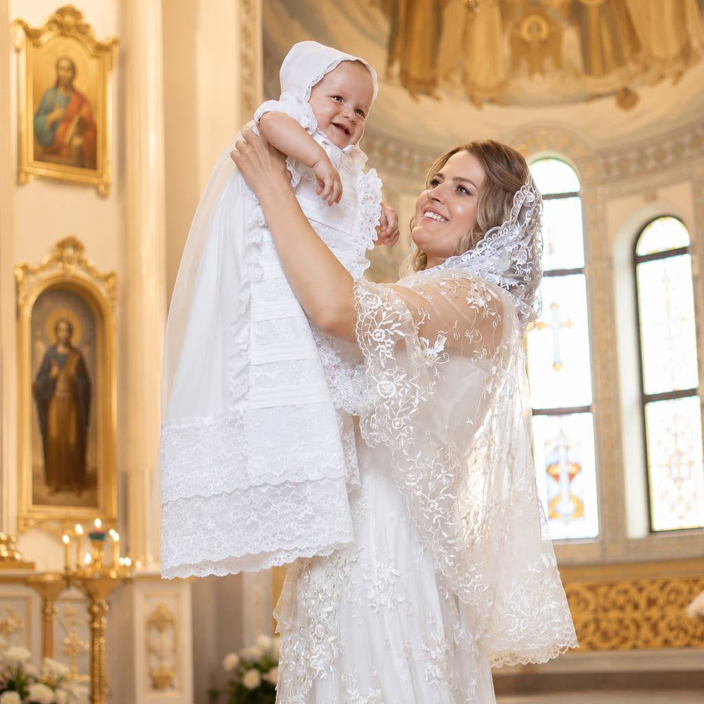 Woman in a white lace dress holding a baby in a church setting