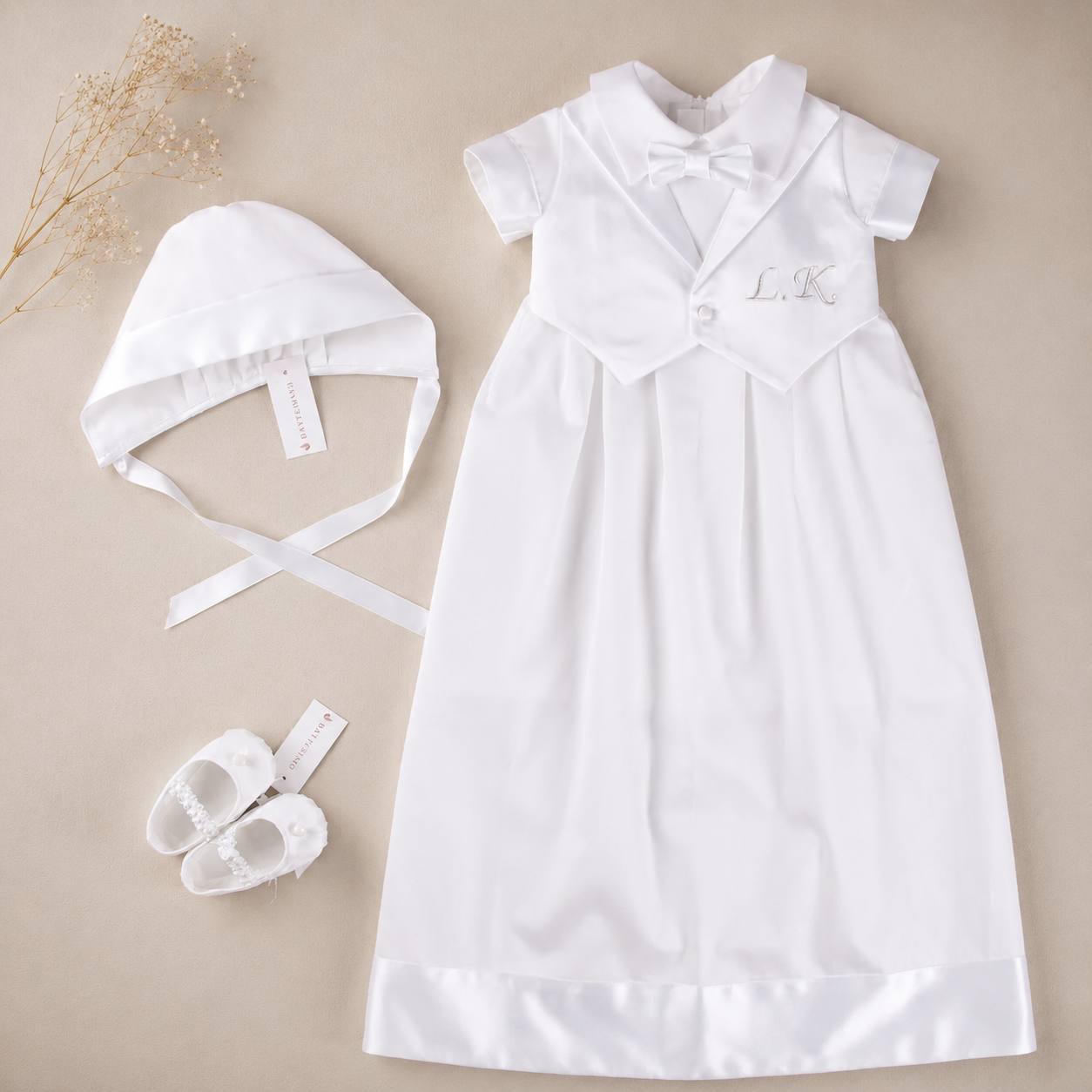 White boy convertible christening romepr with bonnet and shoes on a beige background