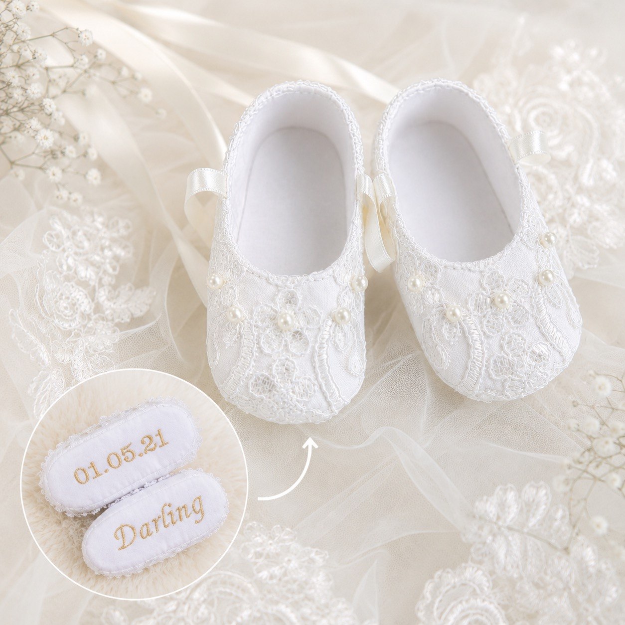 White lace baby shoes with pearl embellishments and ribbon bows, displayed on a soft cream fabric background. A circular inset shows personalized examples with embroidered names and a date.