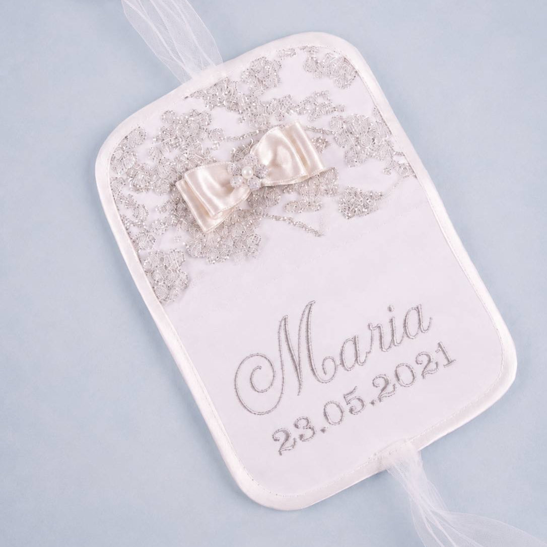 A personalized wedding favor tag with a white satin ribbon bow, delicate silver lace, and custom text reading 'Maria 23.05.