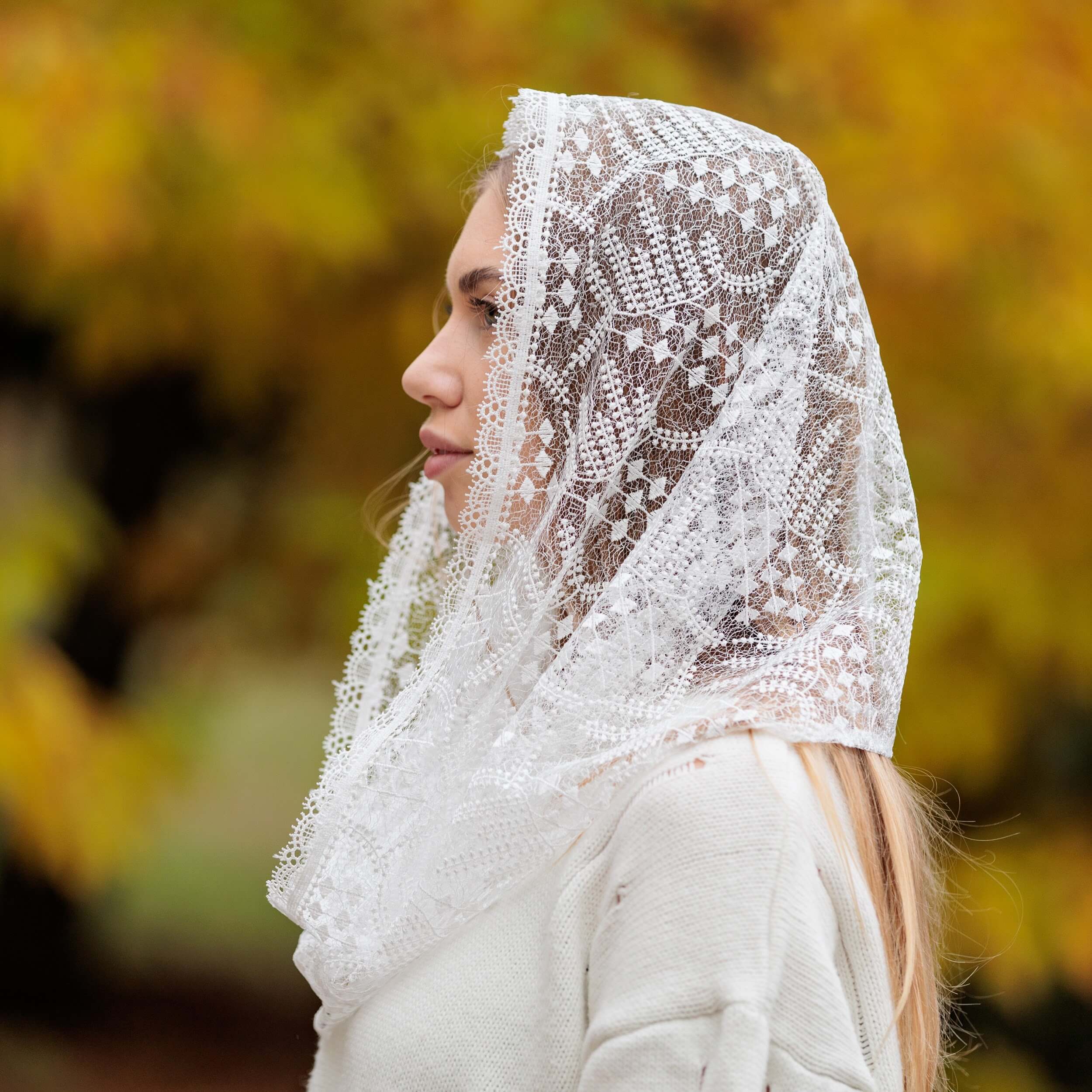 Woman wearing a Catholic Infinity Veil with a blurred autumn background
