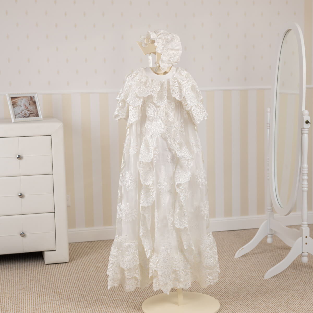 White lace christening set on a mannequin in a room