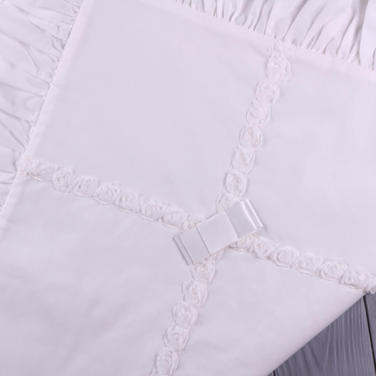 Close-up of a christening blanket with lace trim and a metal clasp.