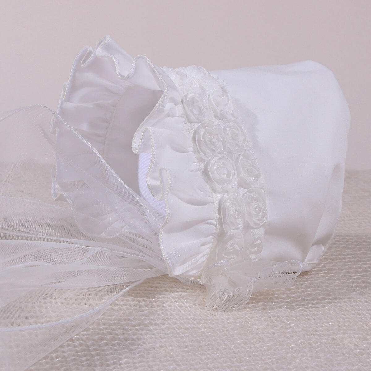 Lace Christening Bonnet with floral embroidery on a beige background