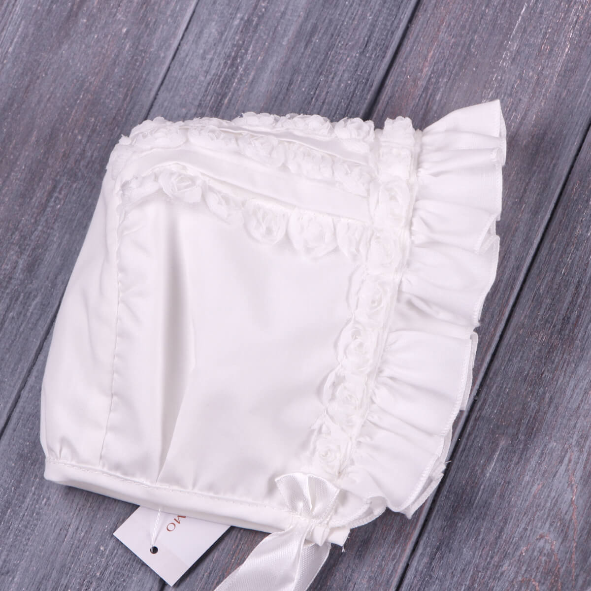 White Lace Christening Bonnet on a wooden surface