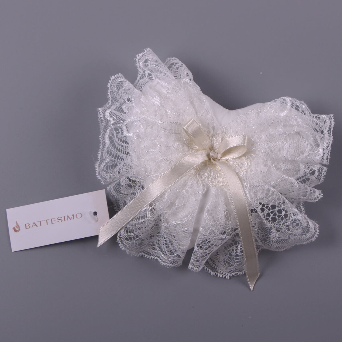 Baptism Cross Pillow with a ribbon on a gray background, featuring the Battesimo brand.