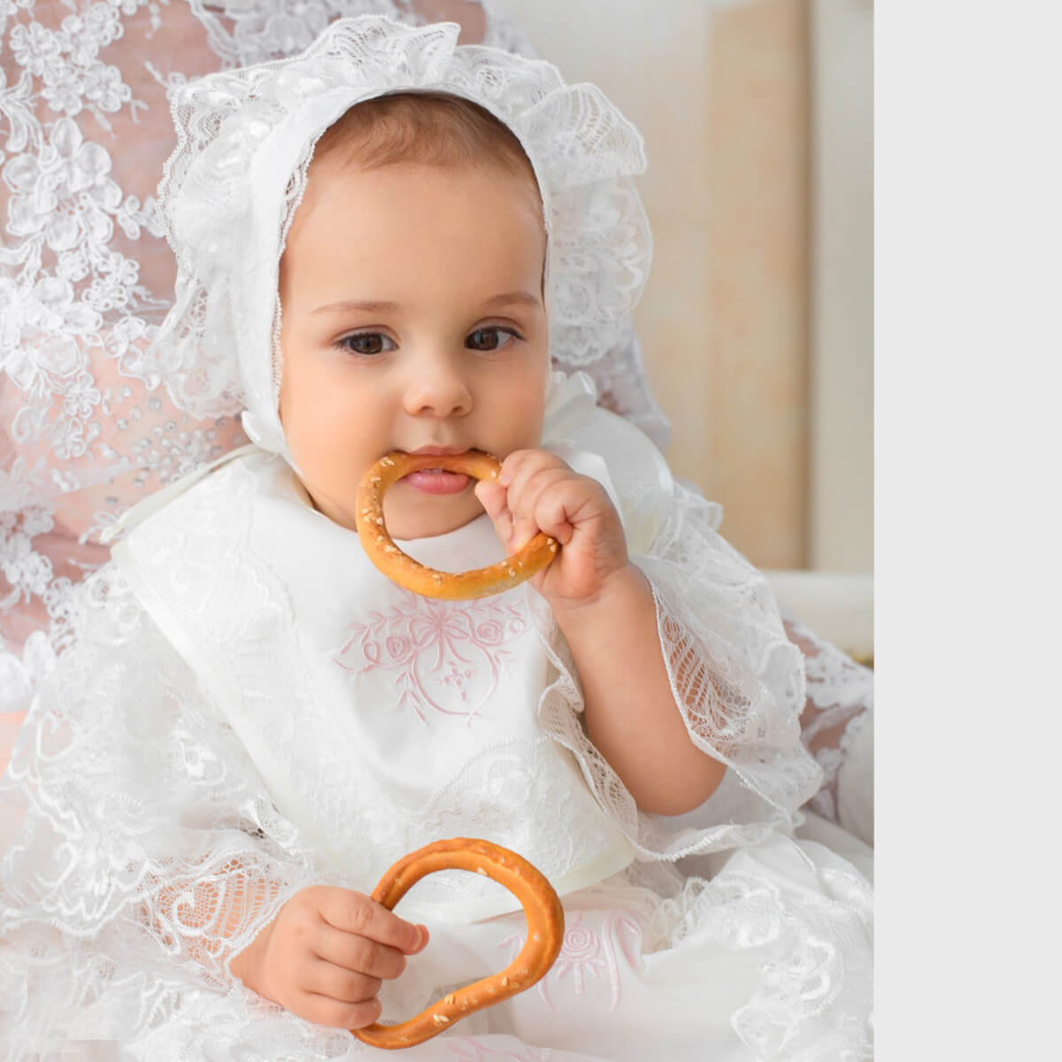 Baby in a Newborn Lace Bib holding a wooden ring