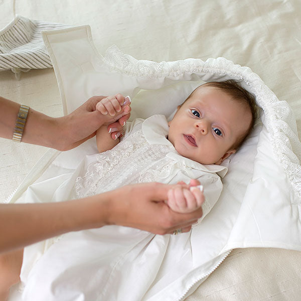 Baby wrapped in a Newborn Sleep Sack with a person's hands holding the baby's feet.