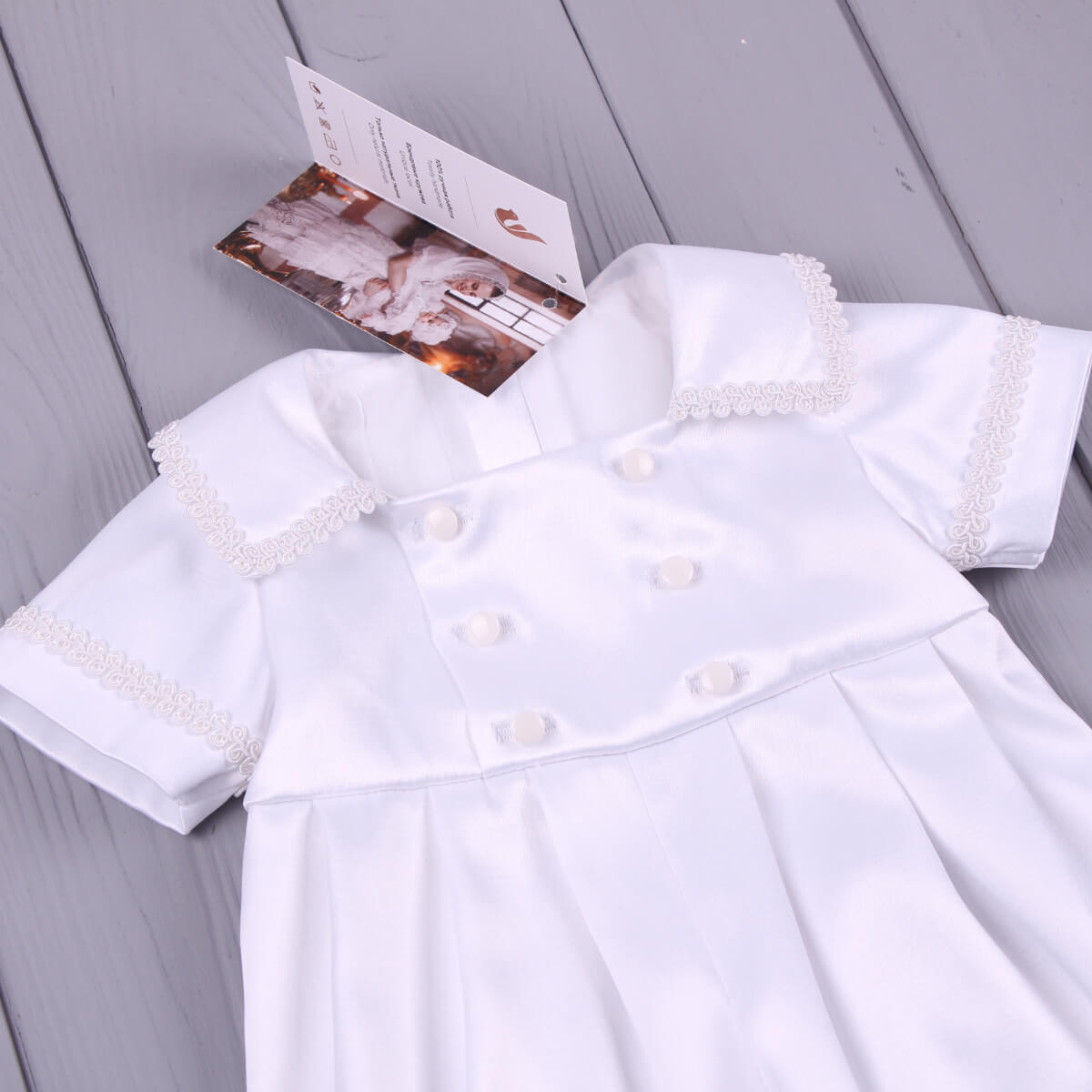 Baby Boy Baptism Romper with pearl details on a gray wooden surface