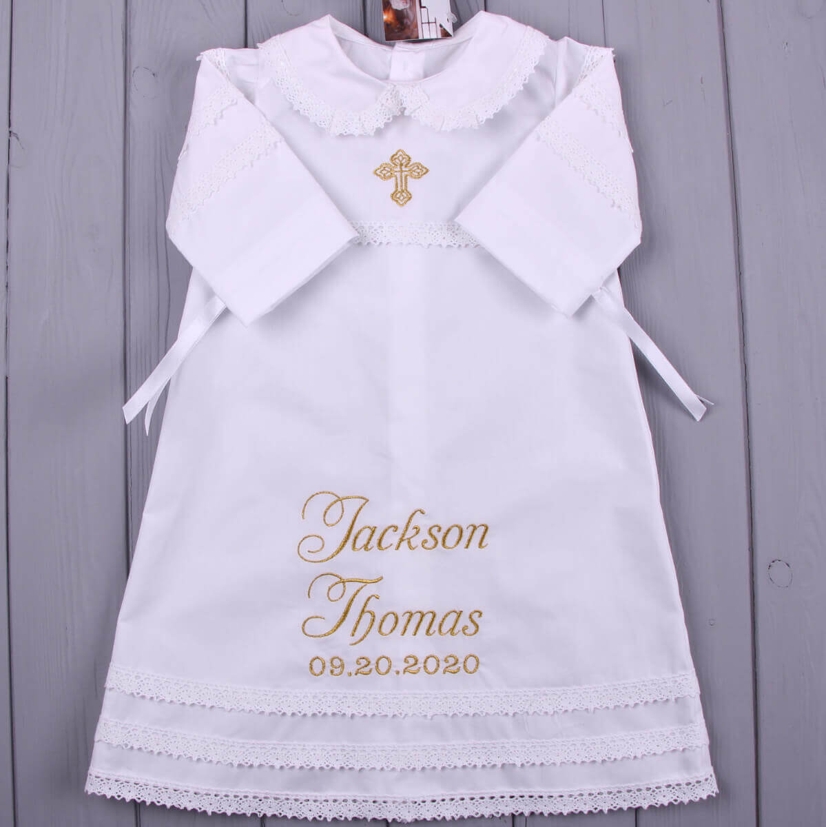 Baptism Gown with embroidered name and date on a wooden background