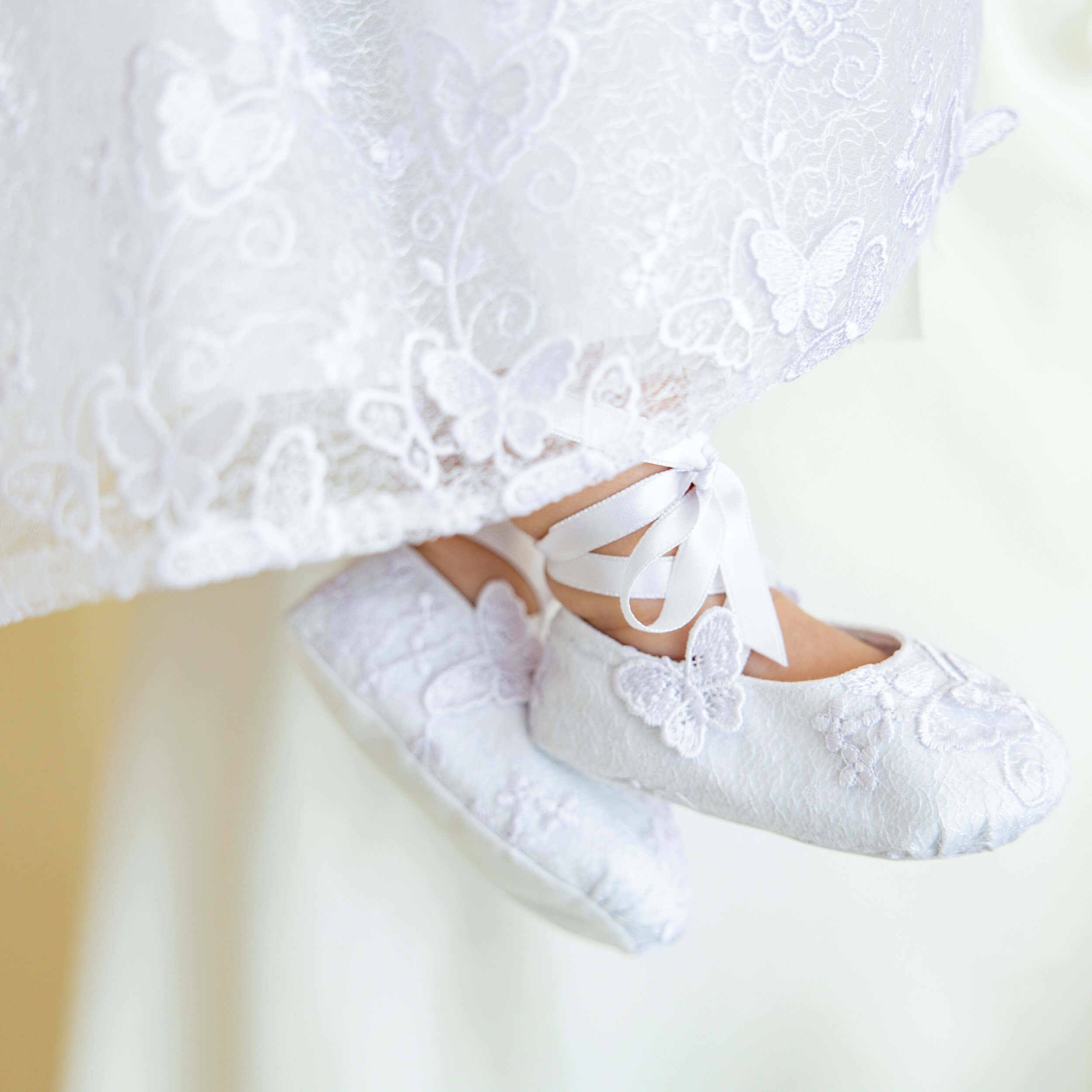 Christening Booties with a white dress in the background