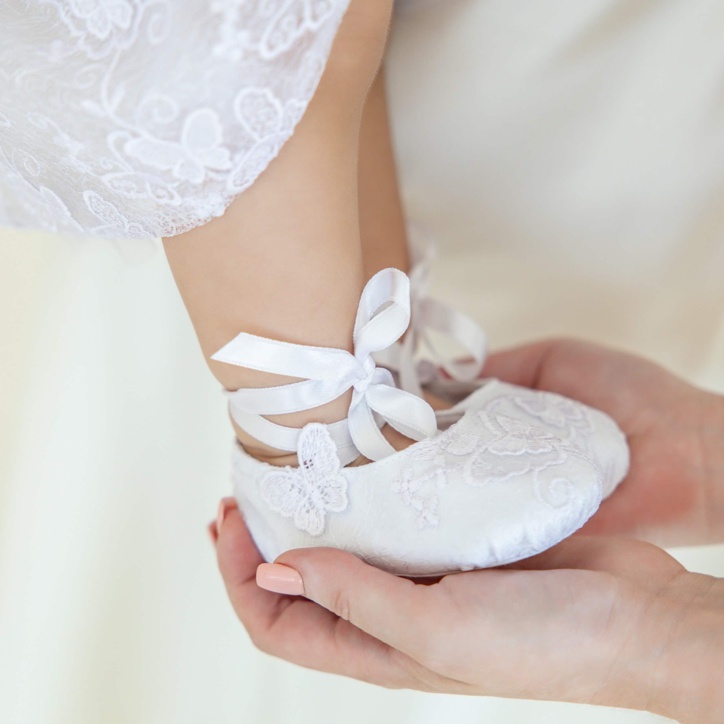 Christening Booties held by a person, with a blurred background