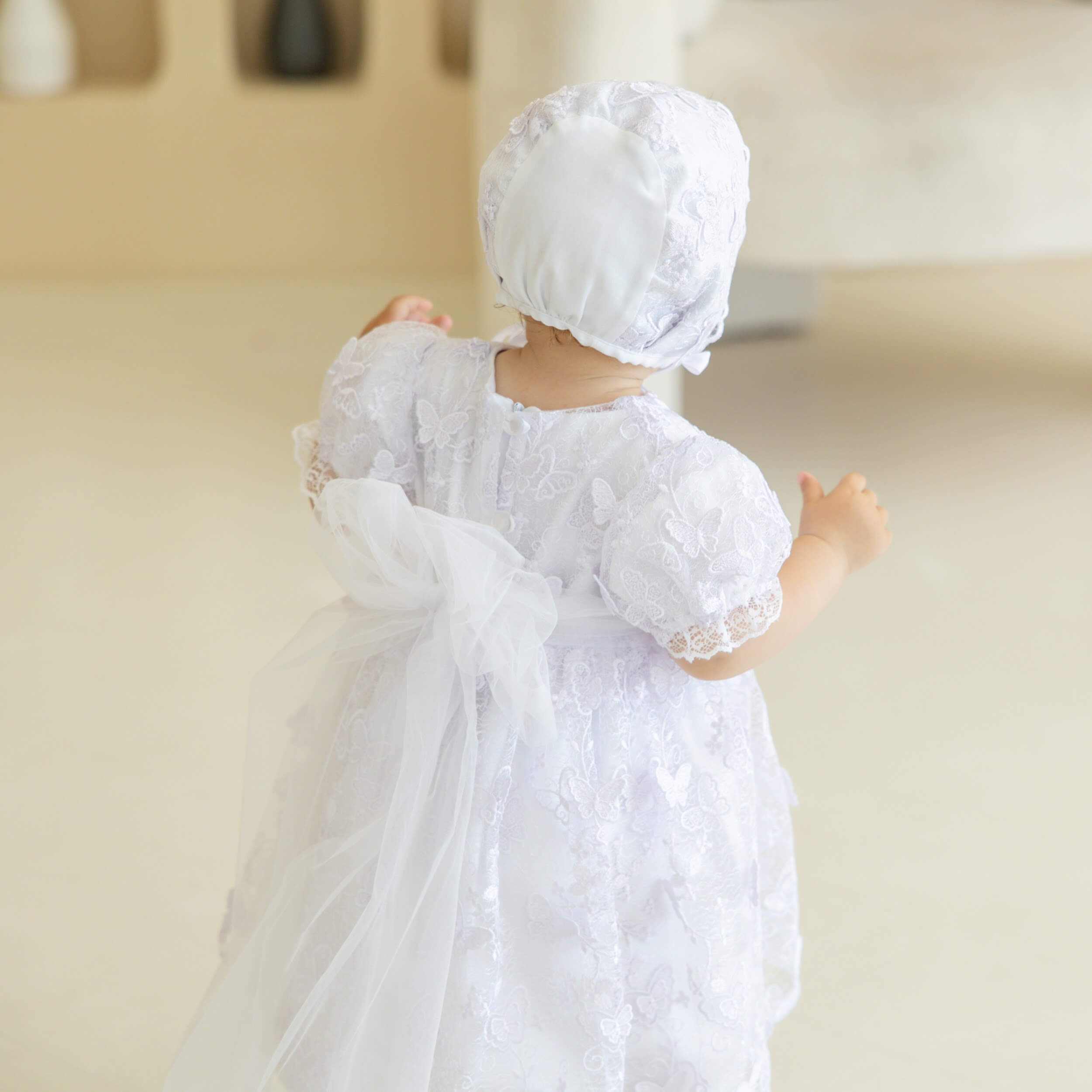 Baby doll in a Baptism Dress with Lace and bonnet on a neutral background