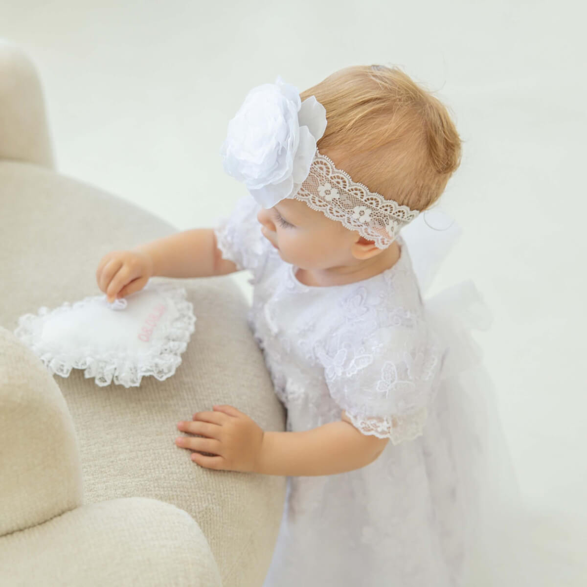 Baptism Ring Pillow on a beige chair.