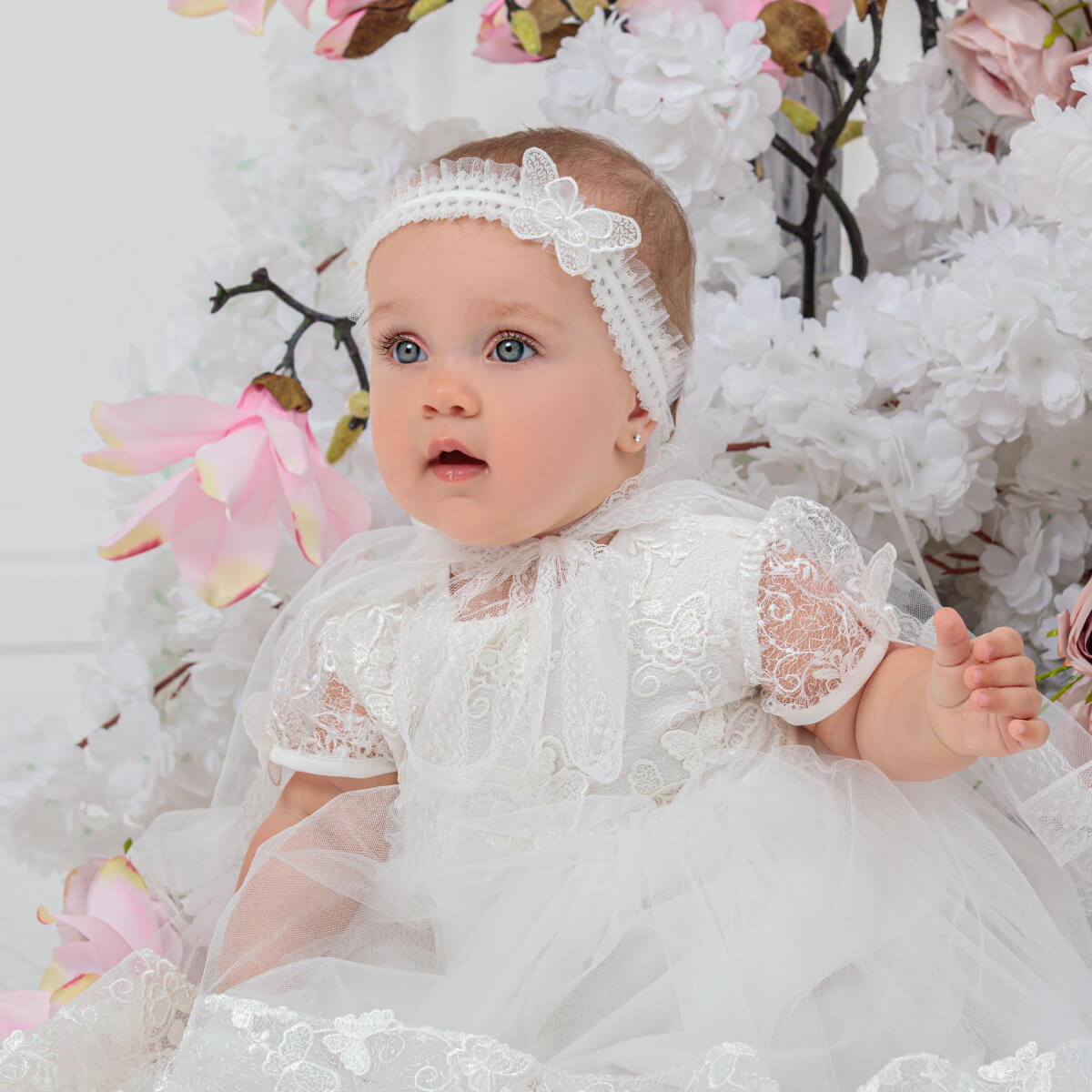 Baby in the baby headband surrounded by floral decorations