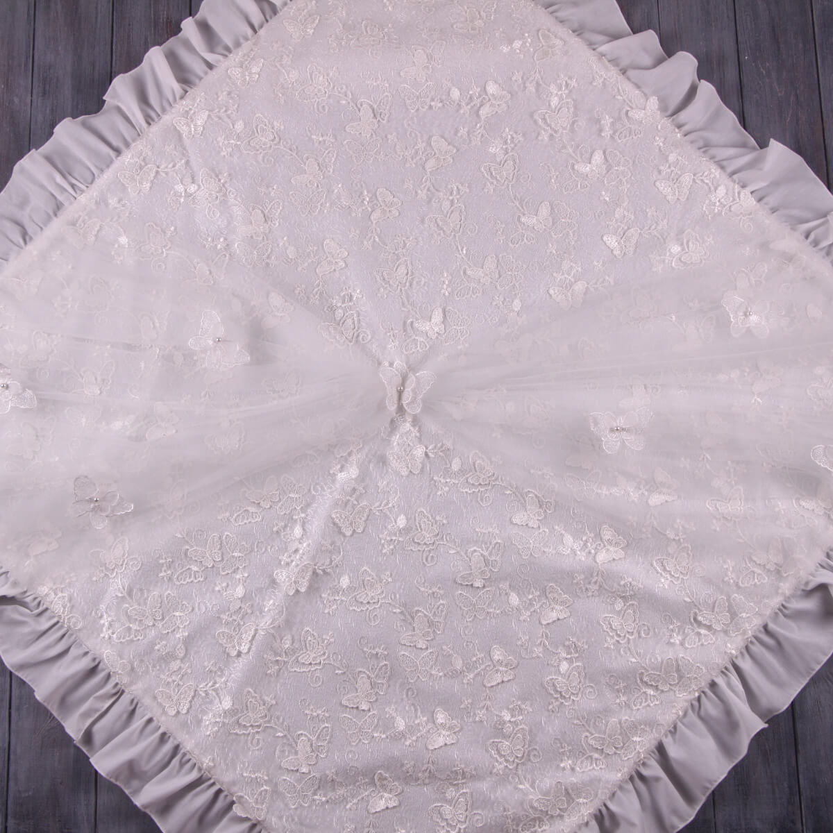 Gray textured christening blanket with floral patterns on a wooden surface