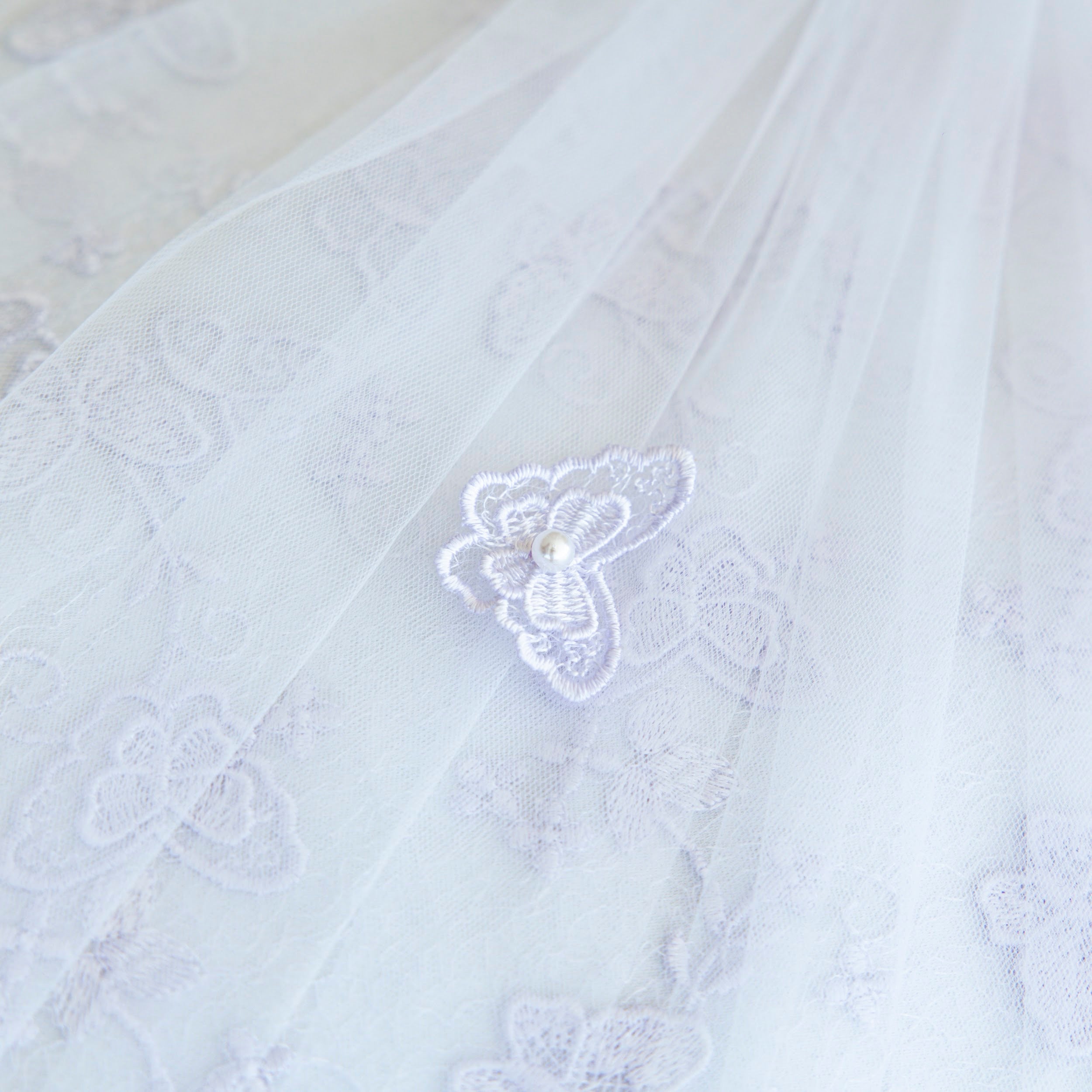 Close-up of a white embroidered christening blanket with a butterfly design.