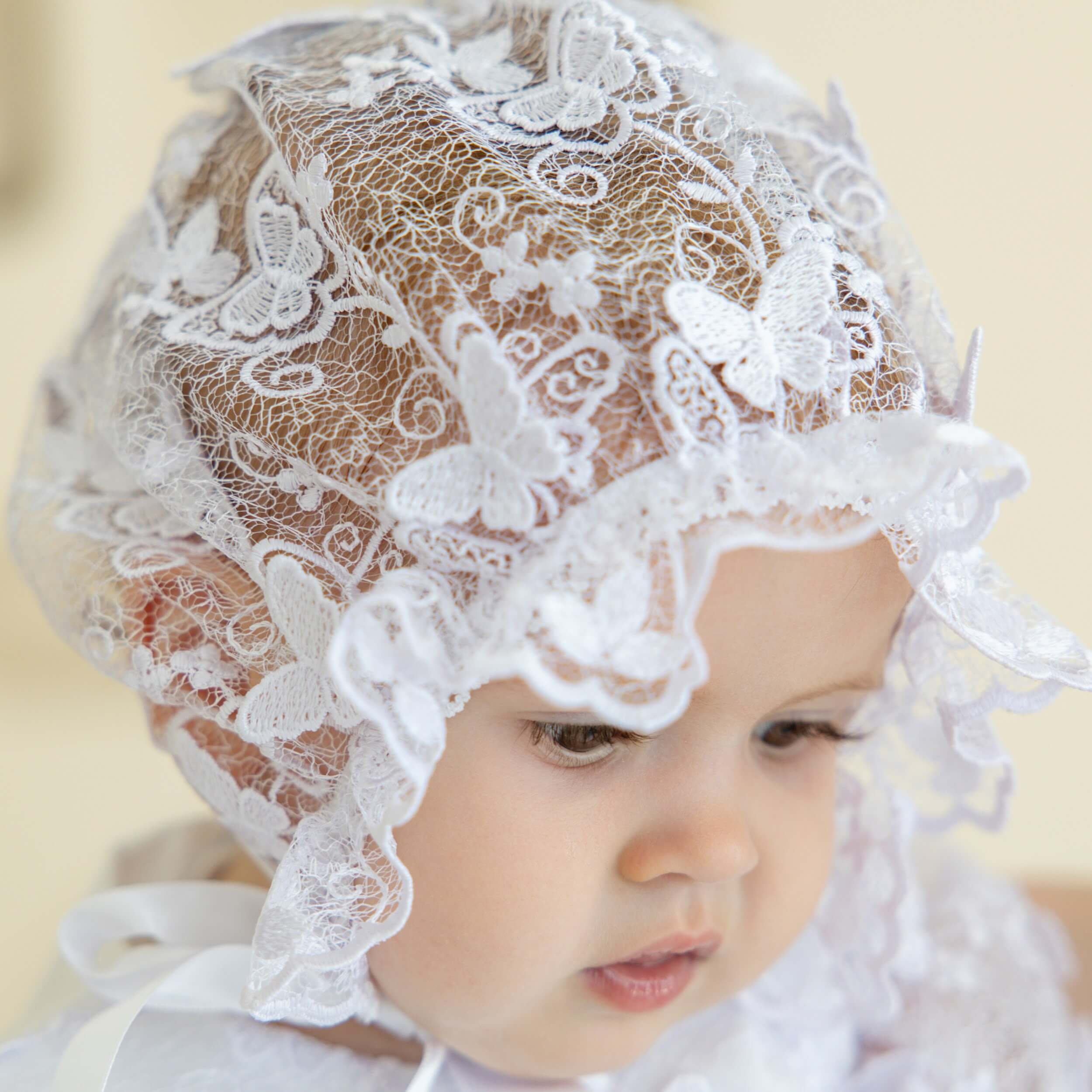 Child wearing a vintage baptism bonnet against a beige background