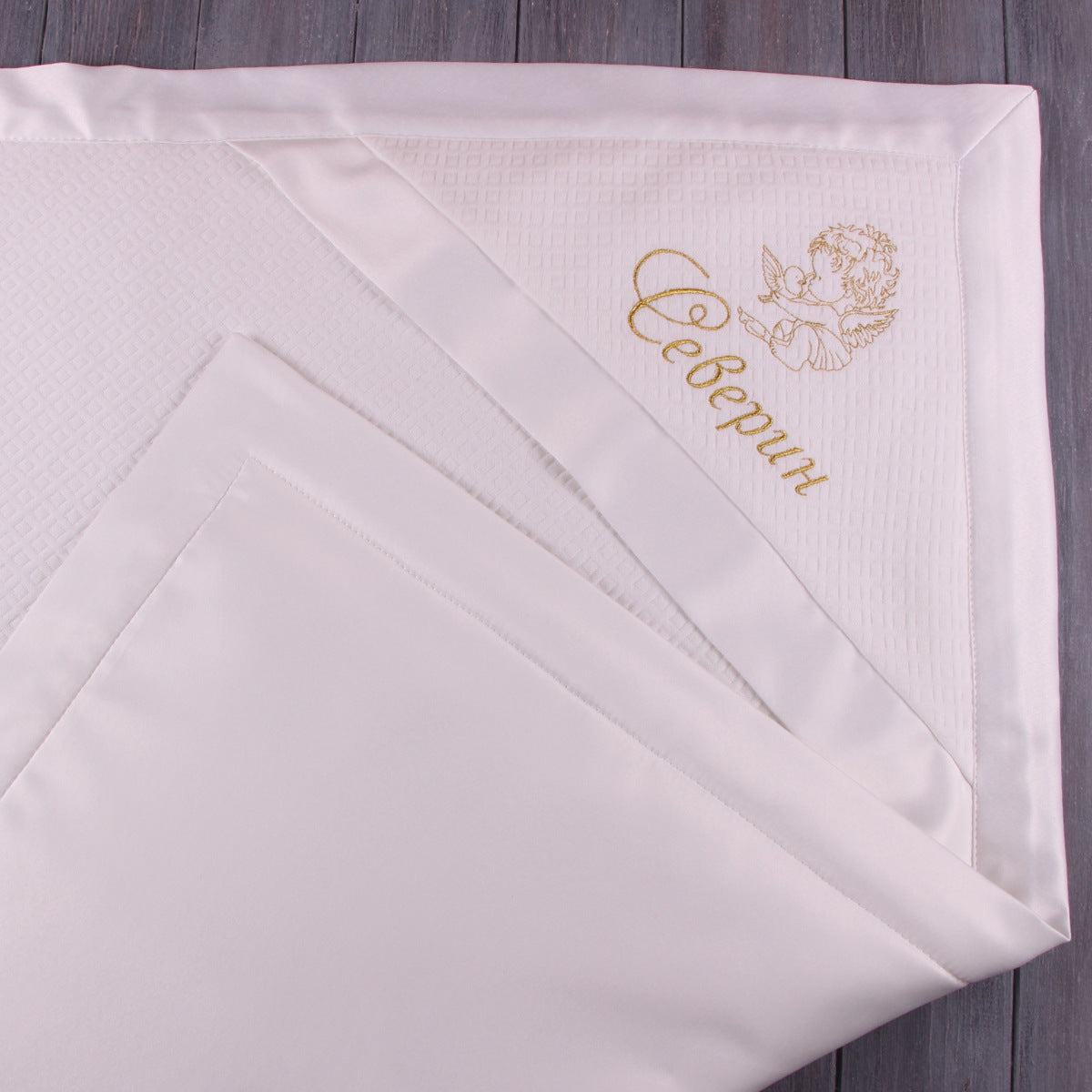 ivory baptism blanket with gold embroidery on a wooden surfaceanket