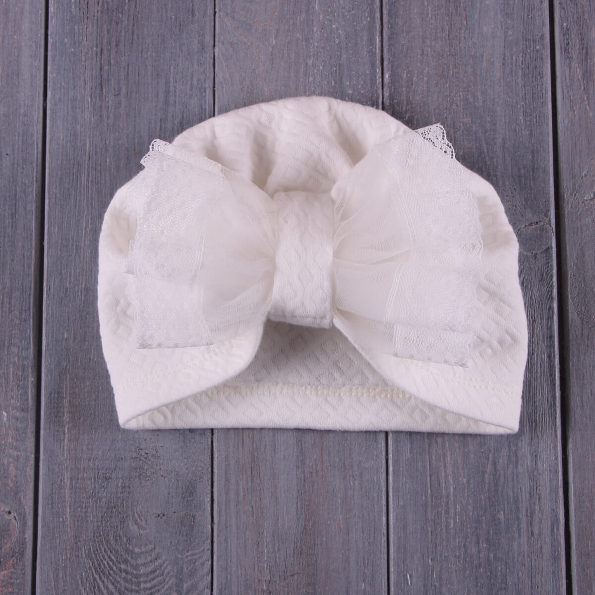 White quilted Lace Christening Bonnet on a wooden surface