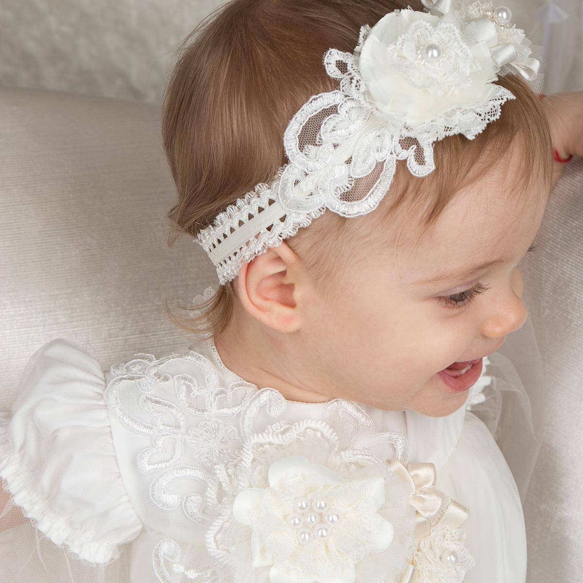 Baby wearing a baby headband and dress with floral details.