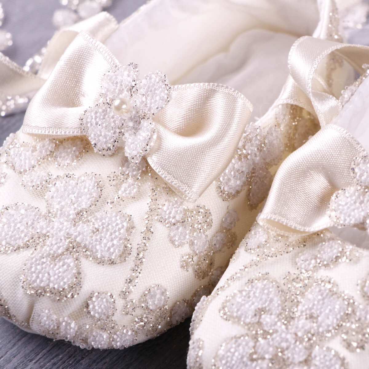 Christening Booties with decorative bows and embellishments on a light background