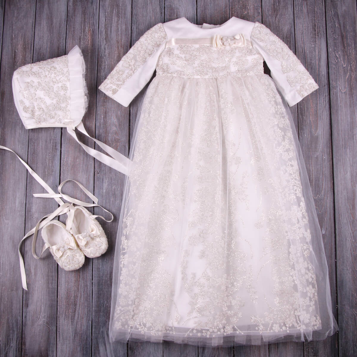 Christening Gown for Girls with matching bonnet and shoes on a wooden background