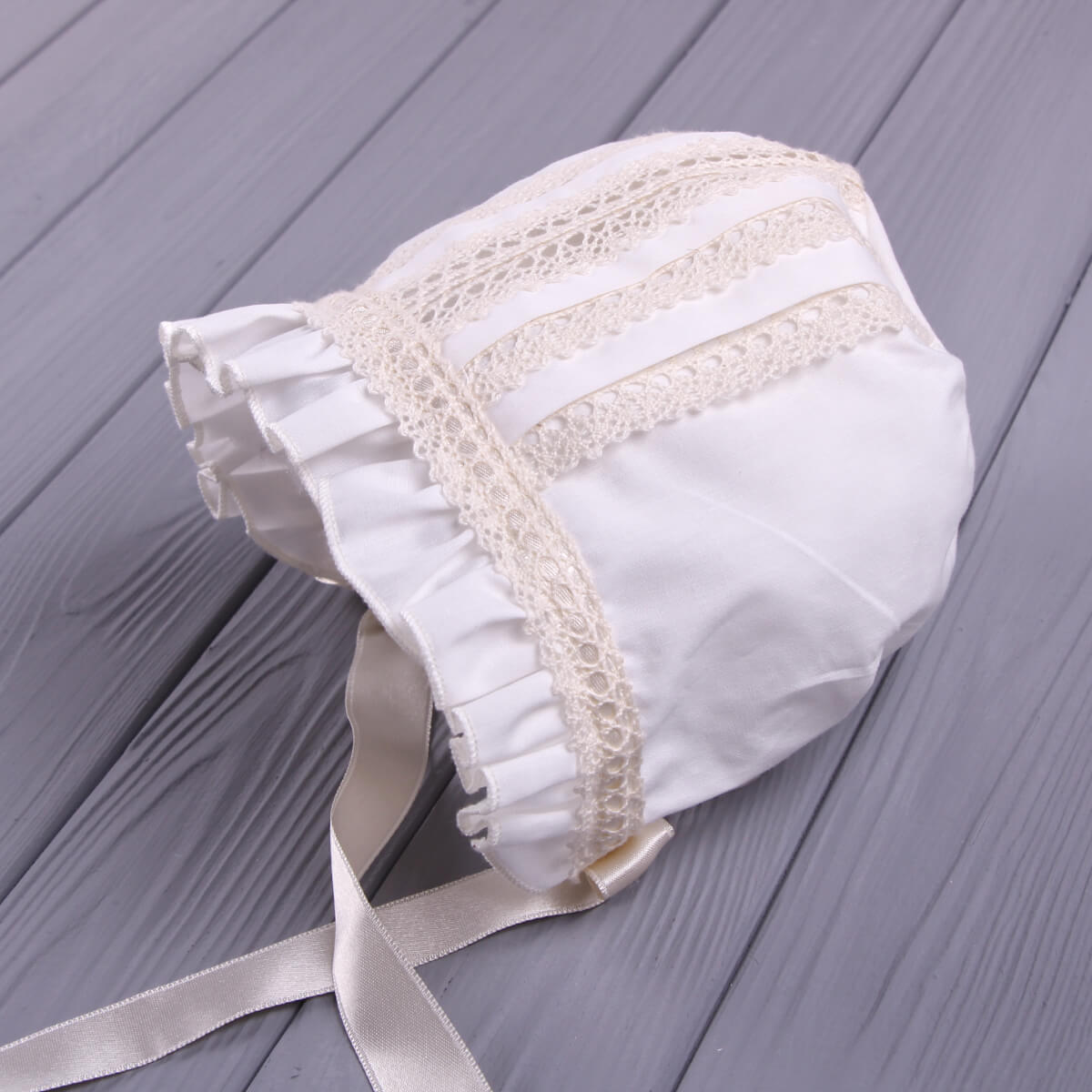 Lace Baptism Bonnet on a gray wooden surface
