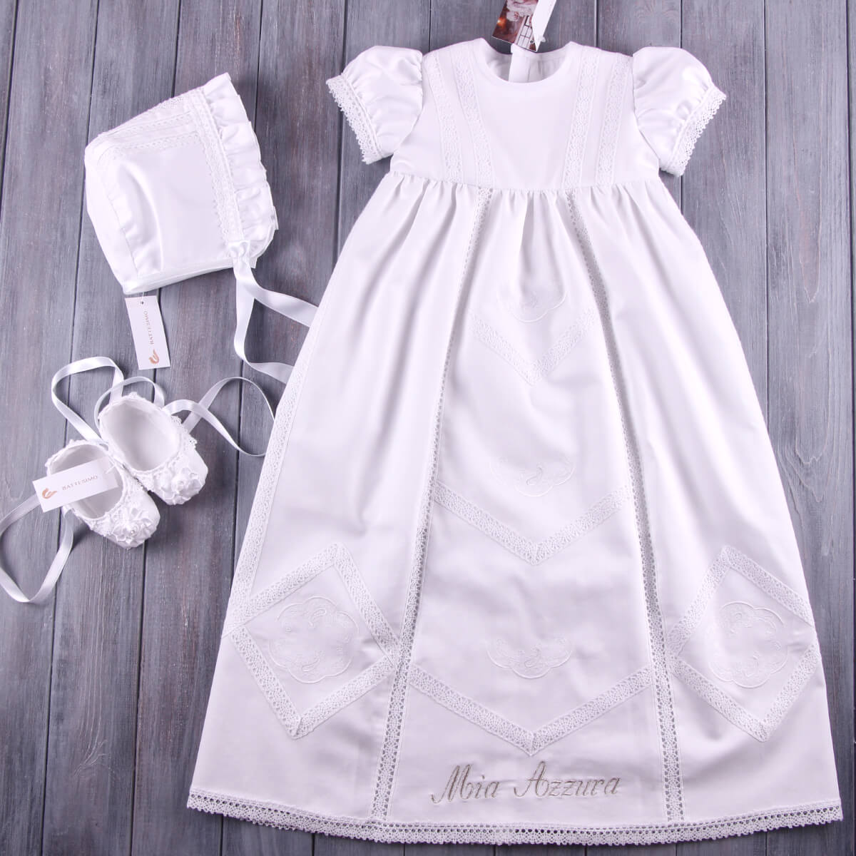 White baby dress with bonnet and Christening Booties on a wooden surface