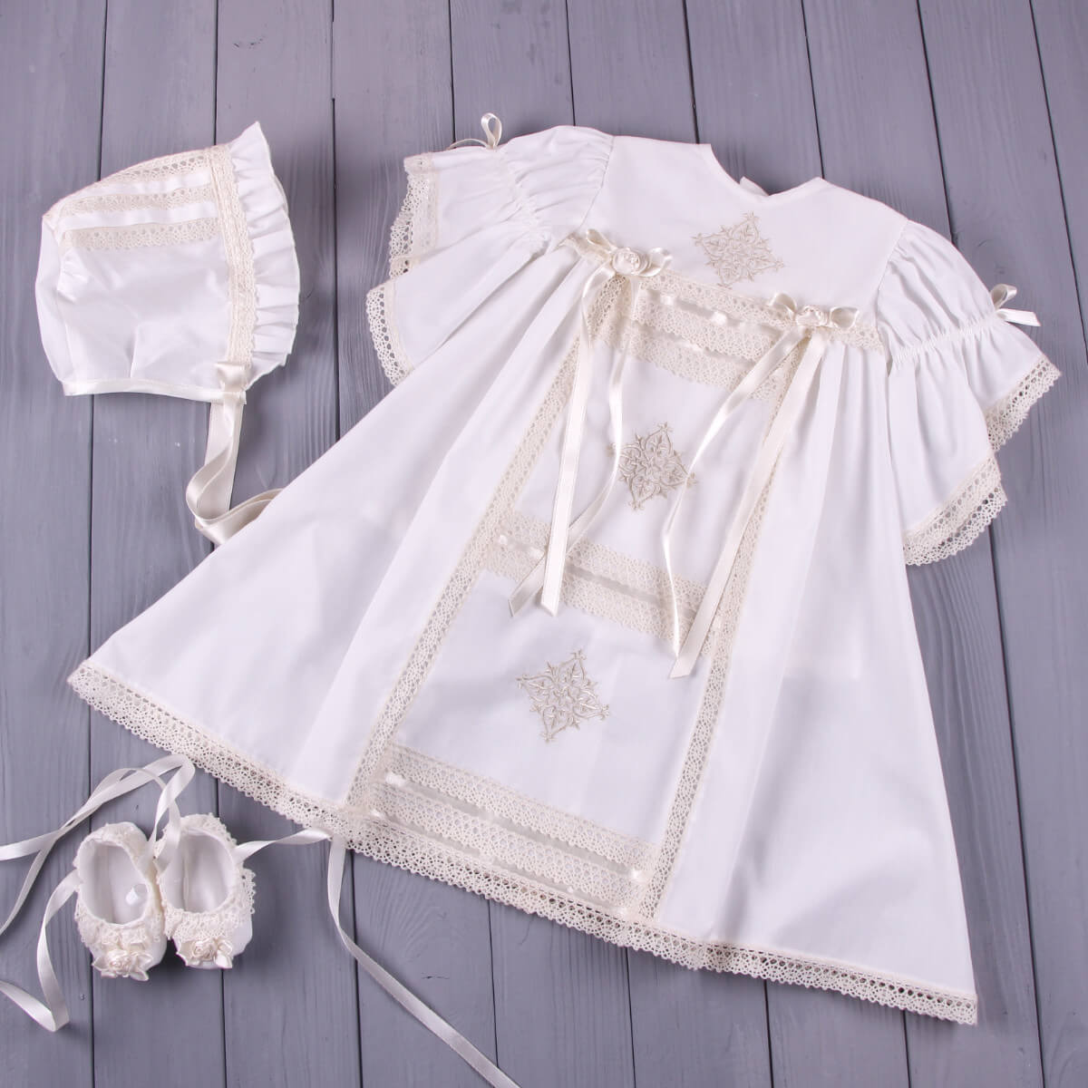 Heirloom Christening Dress drewith lace details, bonnet, and shoes on a wood