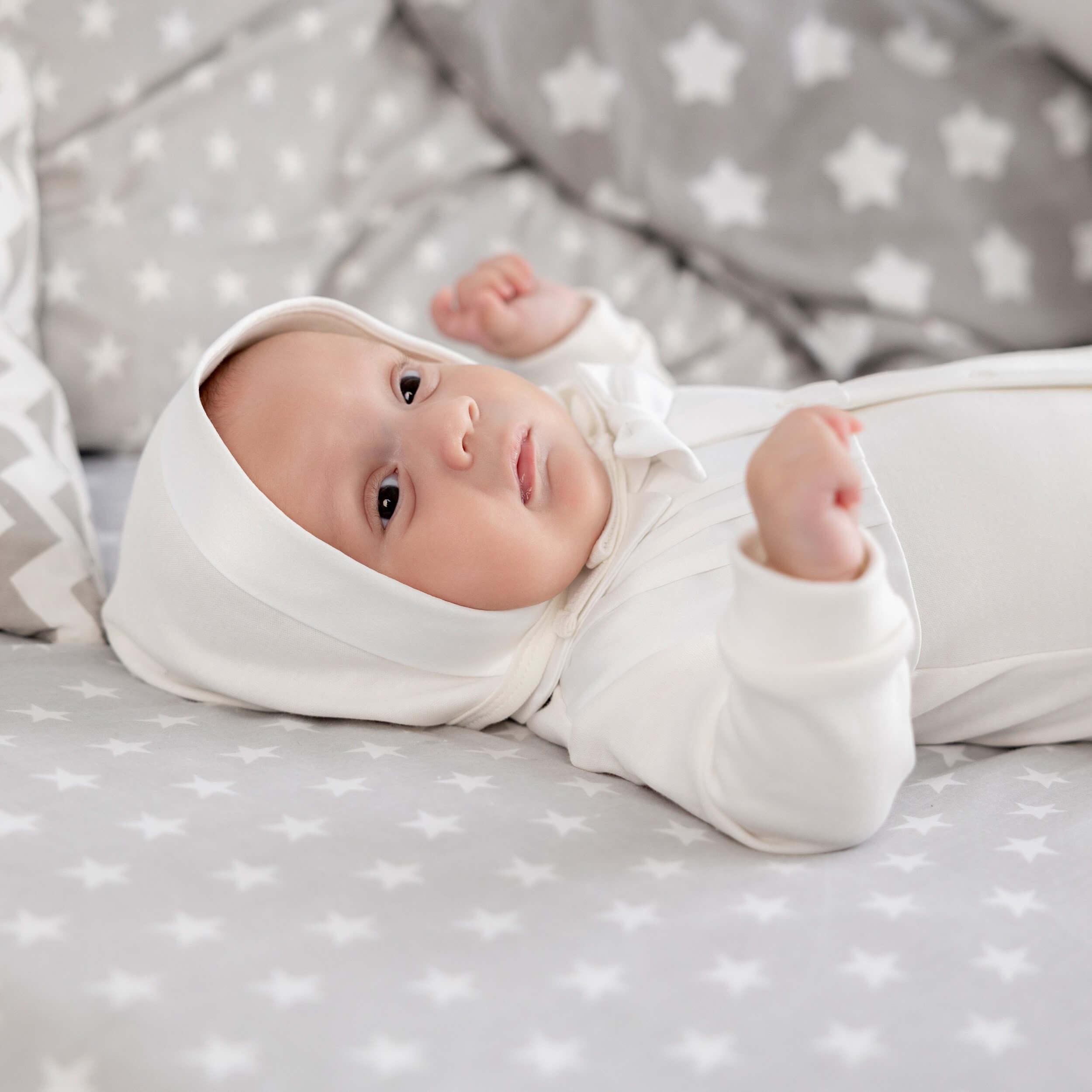 Baby lying on a star-patterned blanket wearing a Newborn Coming Home Suit.