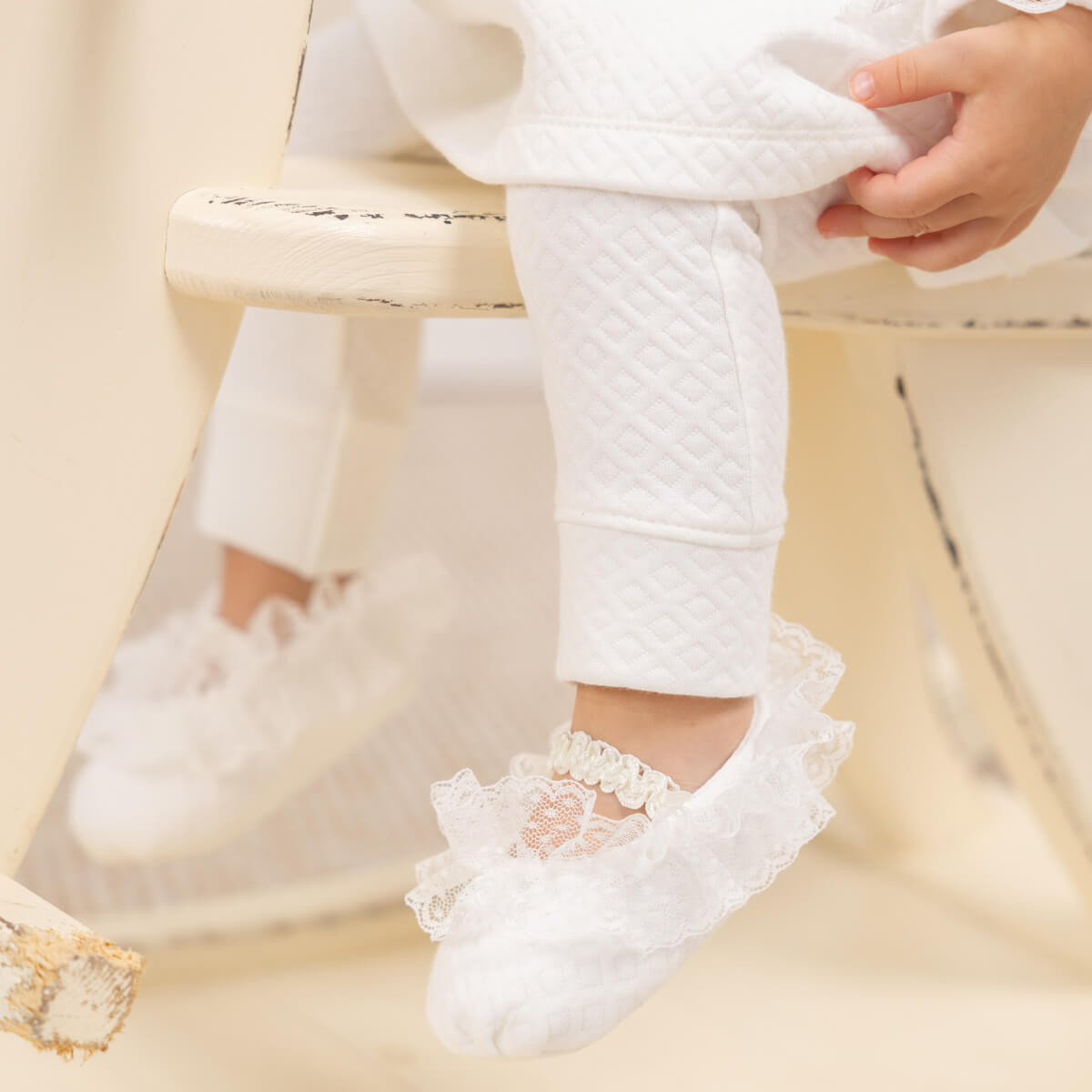 Baby's feet wearing Newborn Coming Home Dress on a light background