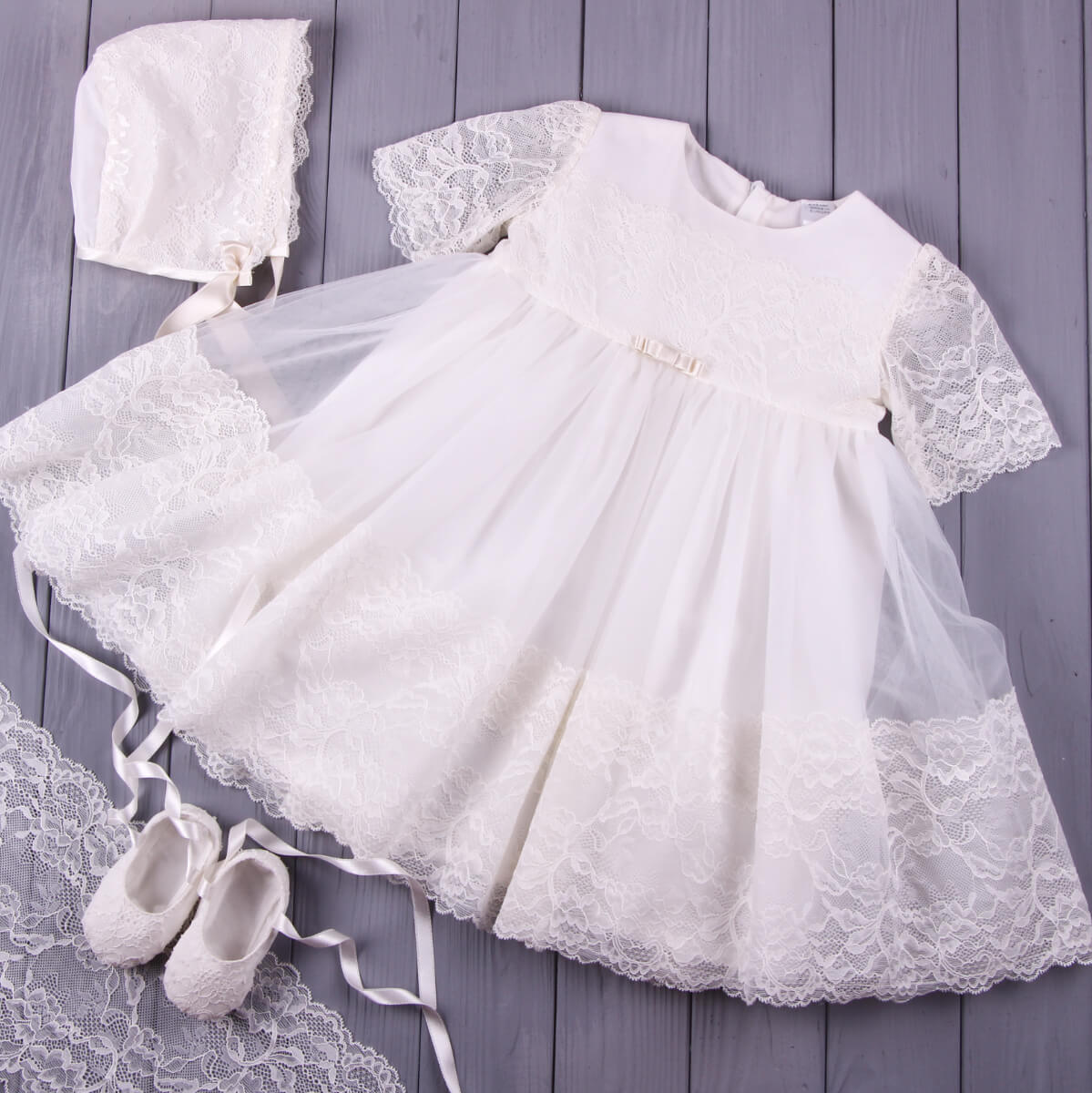 Baptism Tulle Lace Dress with matching bonnet and shoes on a wooden surface
