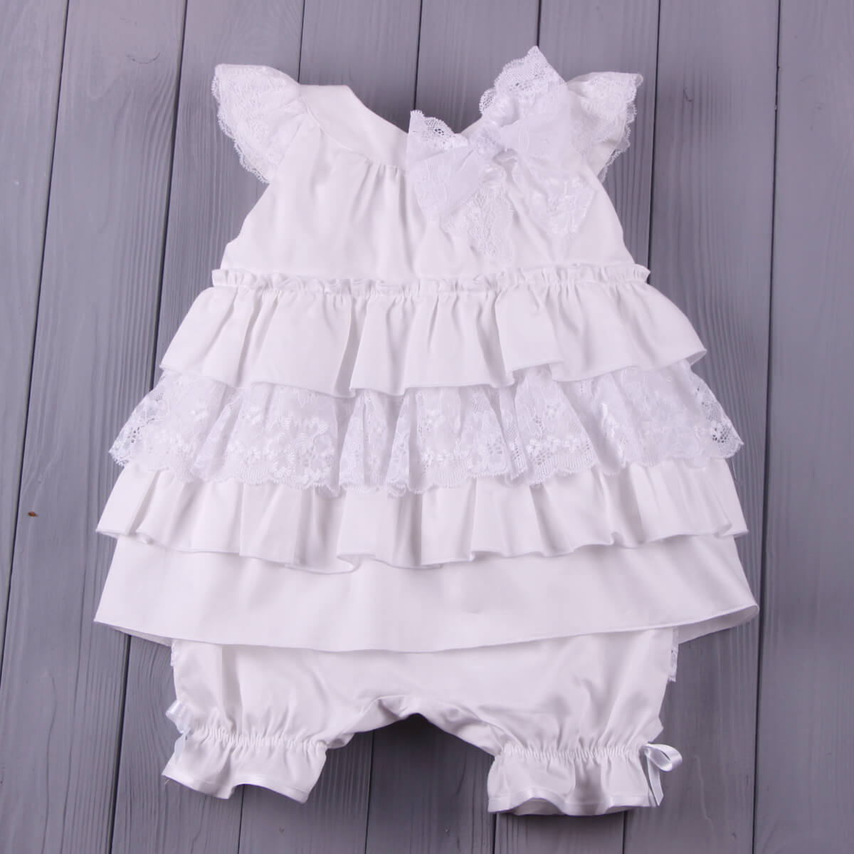 Christening Lace Dress and bloomers on a wooden surface