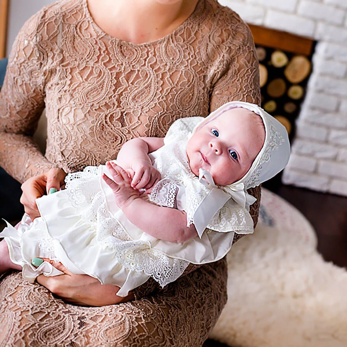 Woman holding a baby dressed in Christening Lace Dresst with a bonnet.
