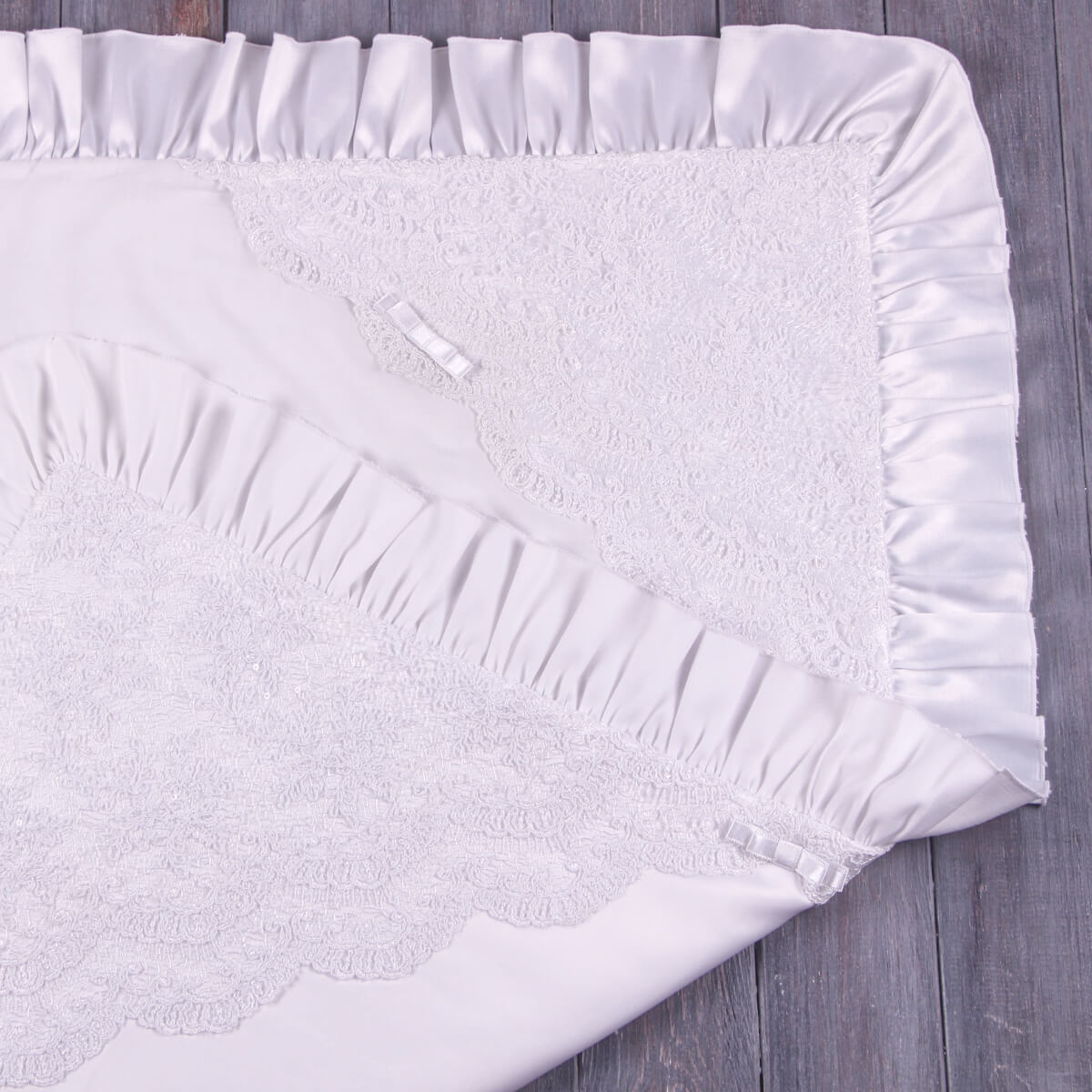 White textured blanket with ruffled edge on a wooden surface