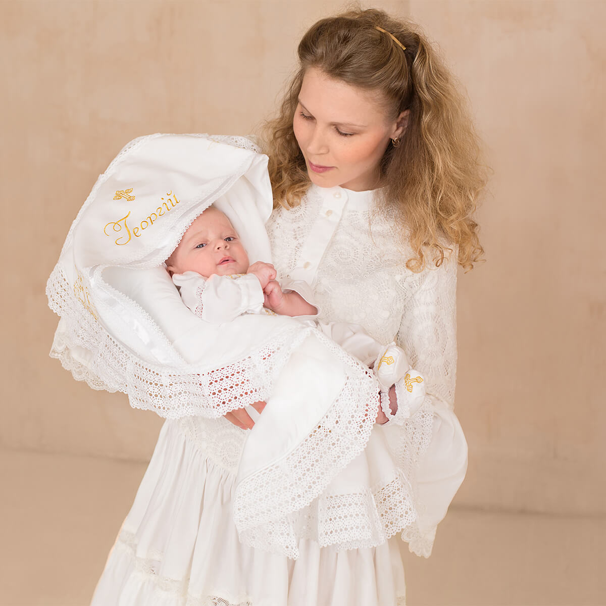 Woman holding a baby wrapped in a white blanket 